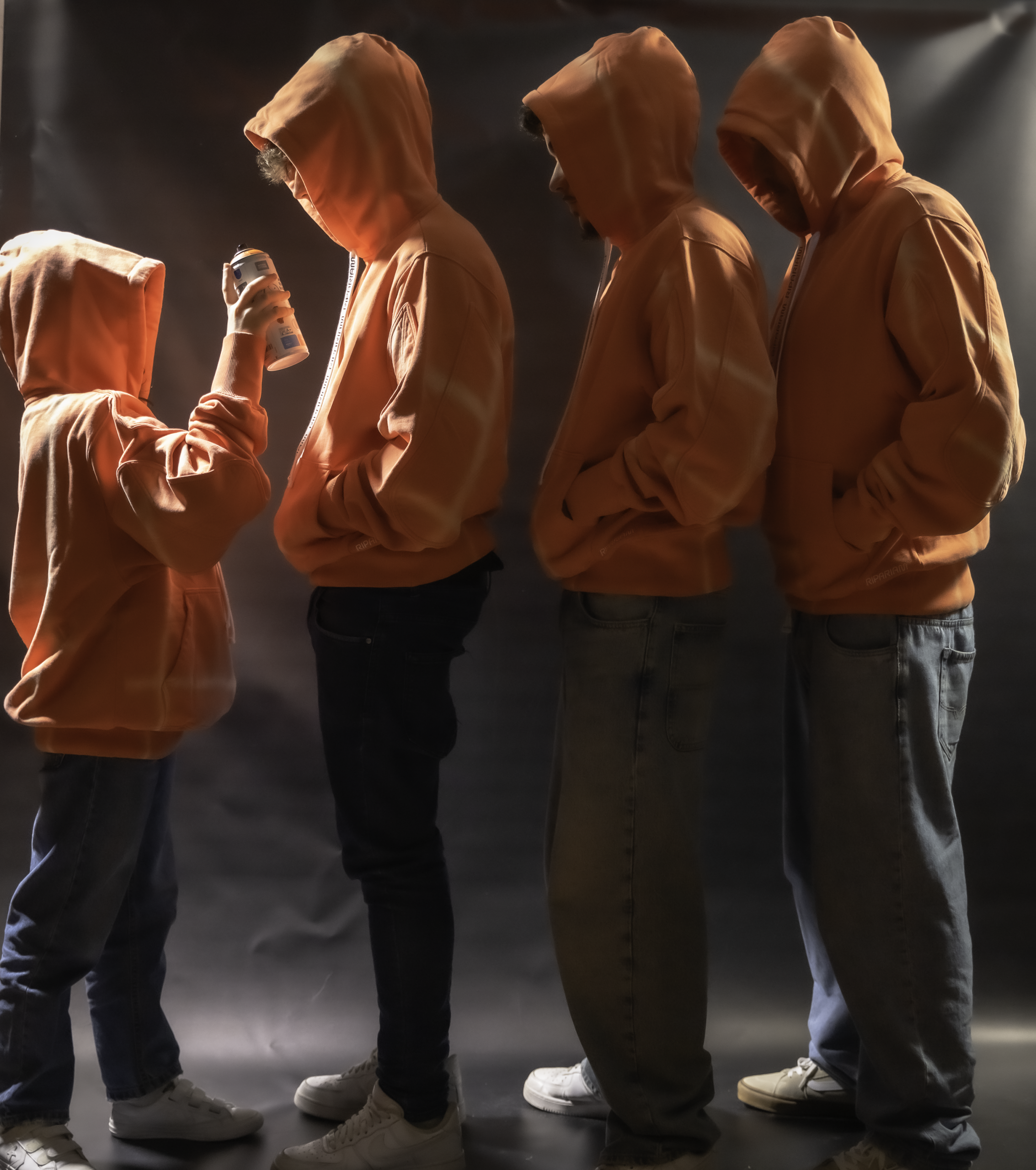 Grupo de personas de diferentes edades con sudaderas naranjas y jeans, imagen de moda urbana y ropa cómoda